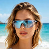 blonde Frau mit blauen photochromen, polarisierten Schutzbrillen am Meer