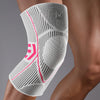 A close-up of a white compression knee support sleeve worn on a person's leg.