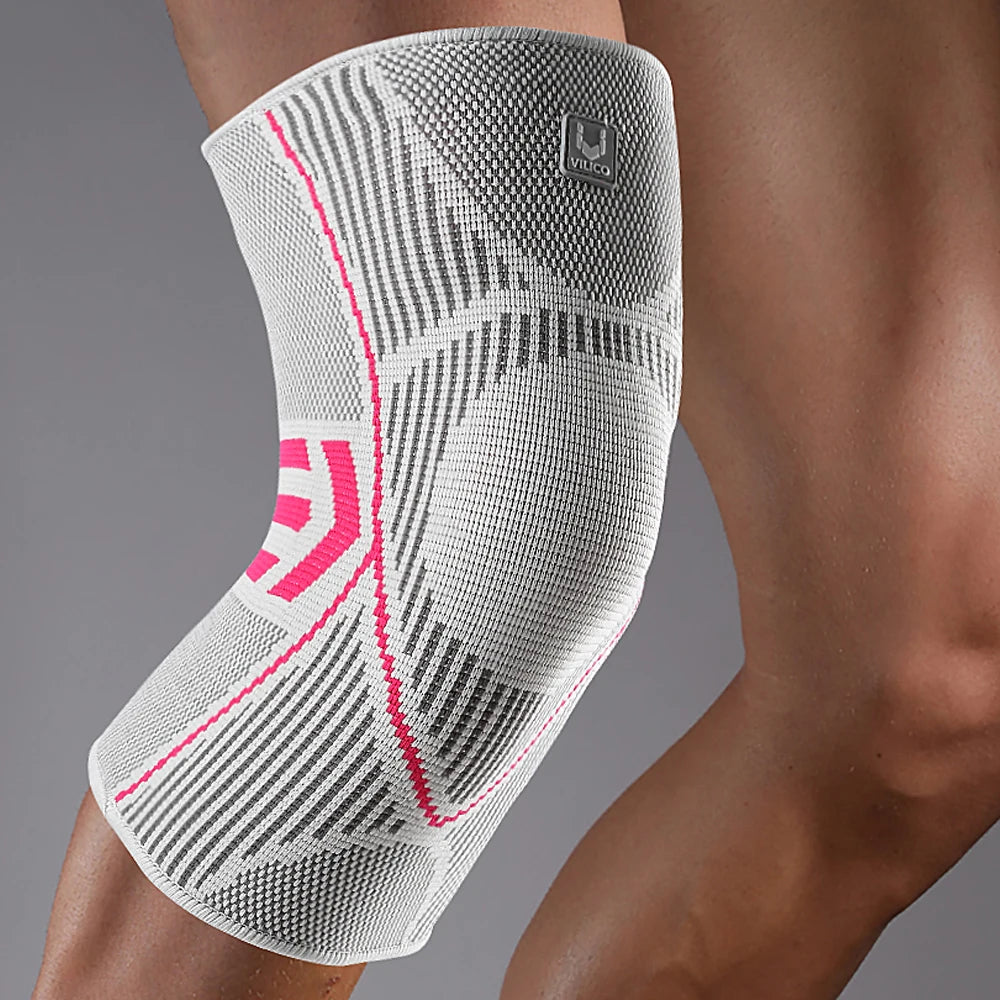 A close-up of a white compression knee support sleeve worn on a person's leg.