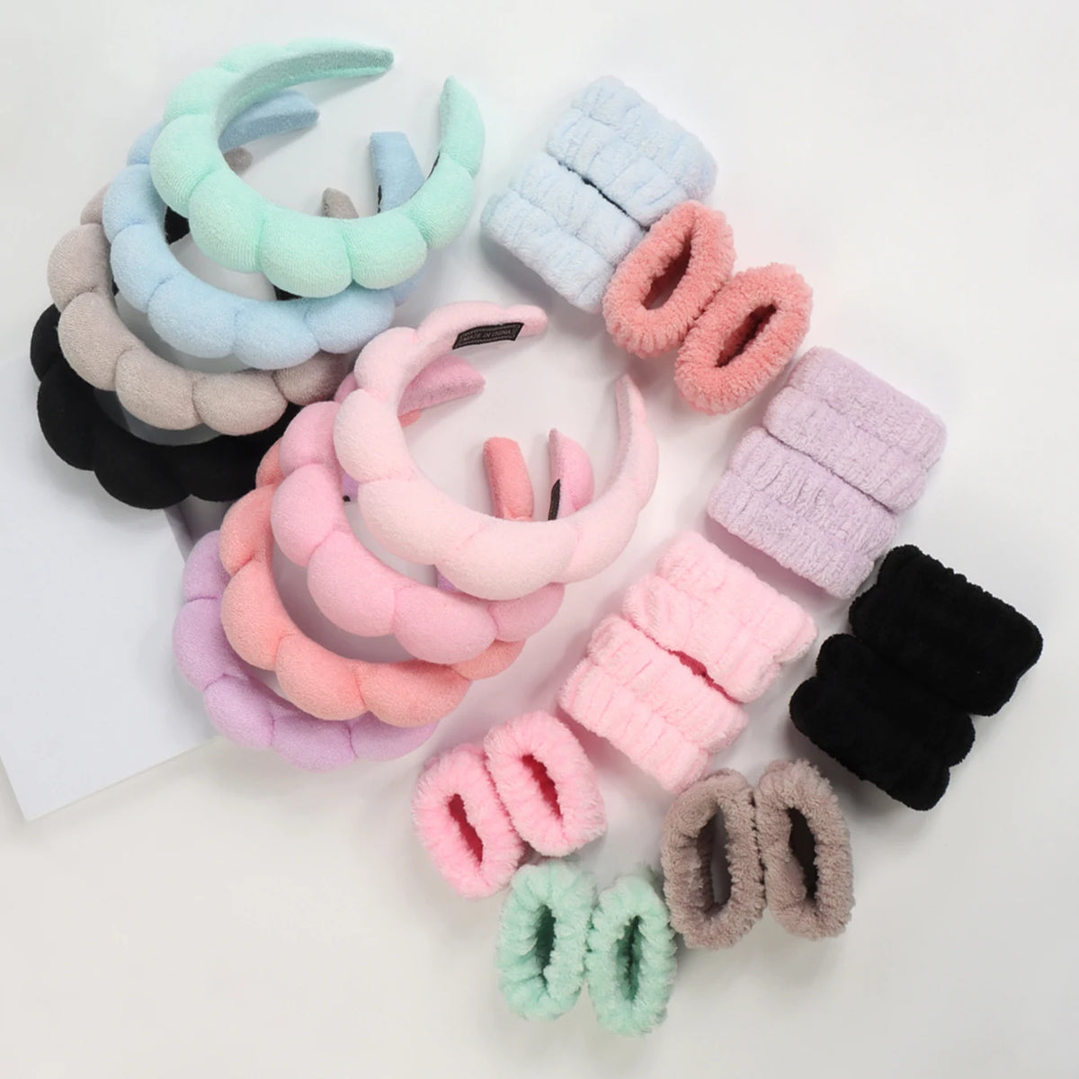 A collection of colorful microfiber skincare headbands and wristbands in shades of blue, pink, purple, and black.