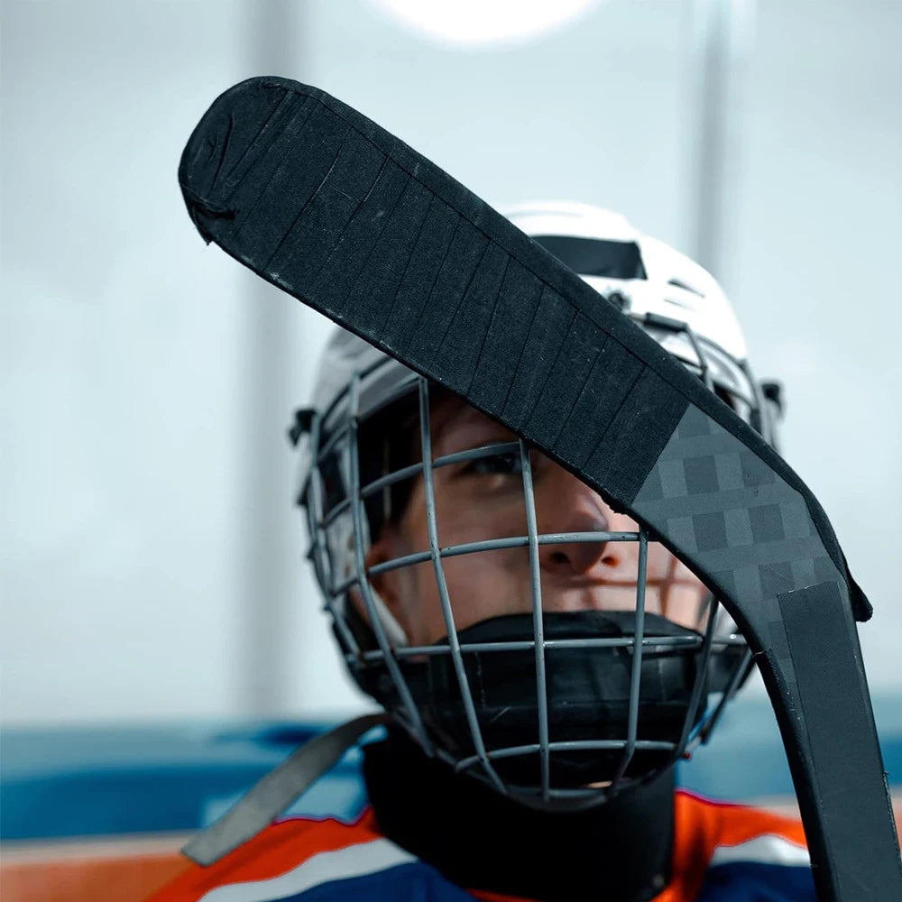 Nahaufnahme einer Person mit Hockeyhelm, die eine schwarze Griffbandrolle für Sportausrüstung hält.