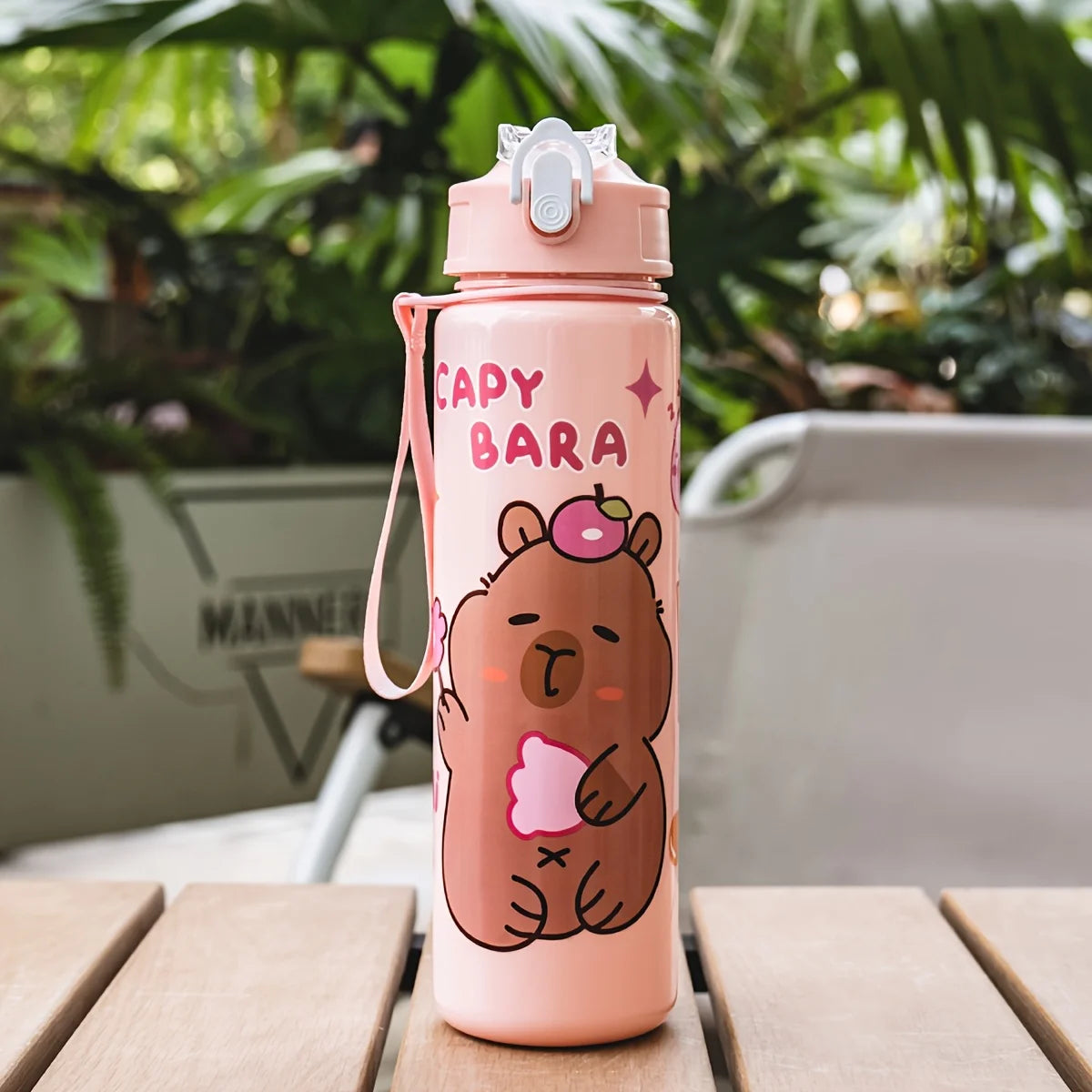 A pink cartoon drinking water bottle with a bear design and a silver cap, set on a wooden surface.