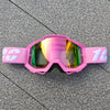 Lunettes de moto tout-terrain roses avec marquage blanc posées sur une surface grise.