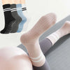 Primer plano de cuatro pares de calcetines de yoga y pilates antideslizantes para mujer en varios colores apilados.