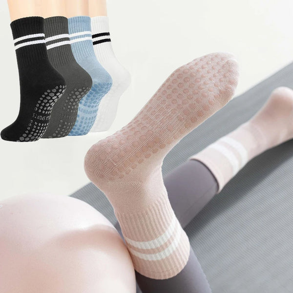 A close-up view of four pairs of women's non-slip yoga and pilates socks in various colors stacked together.