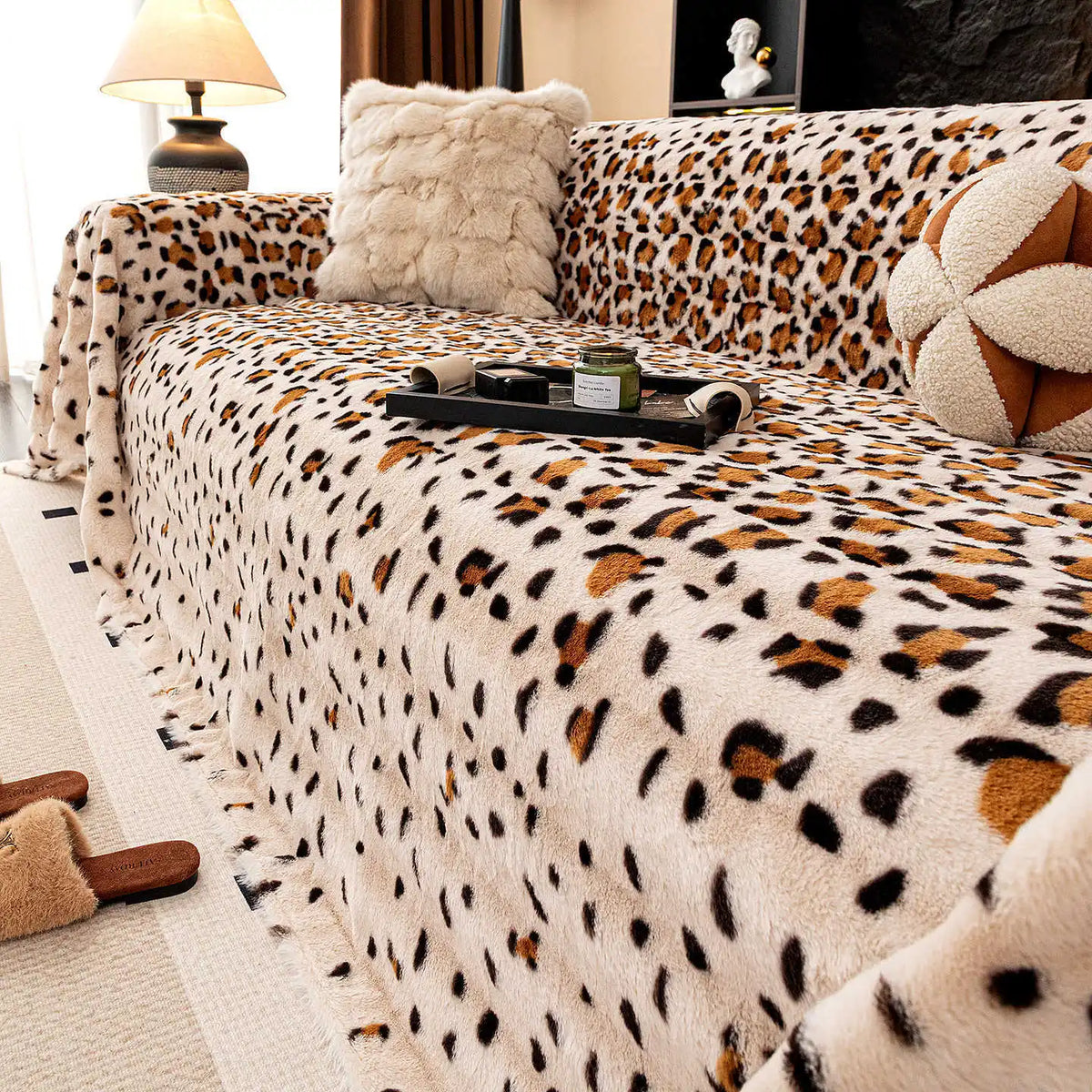 A plush leopard print sofa cover blanket draped over a sofa with decorative pillows and accessories.