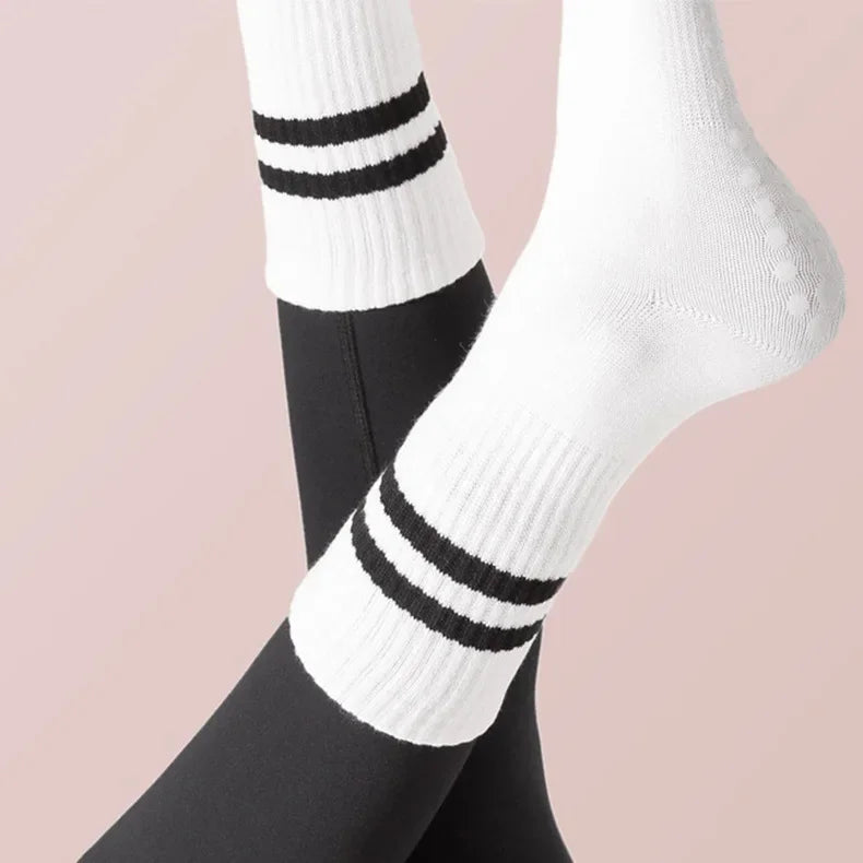 White ribbed yoga socks with black stripes worn on a foot against a light background.