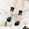 A pair of sheer black lace socks worn on a person's feet against a white background.
