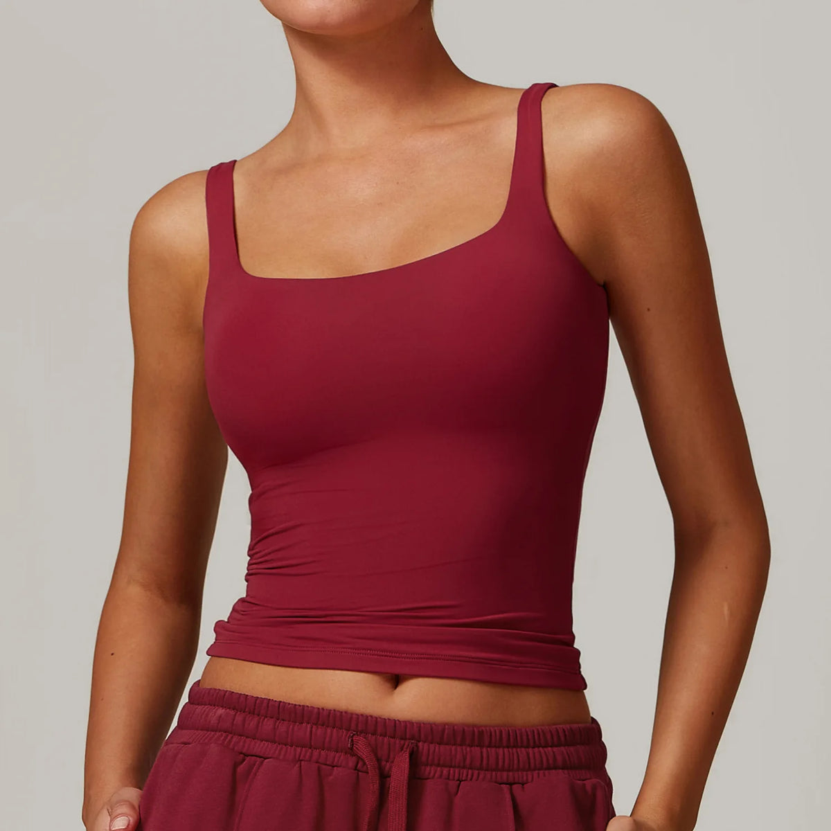 Una modelo vistiendo un top deportivo de cuello cuadrado color granate y la parte inferior a juego.