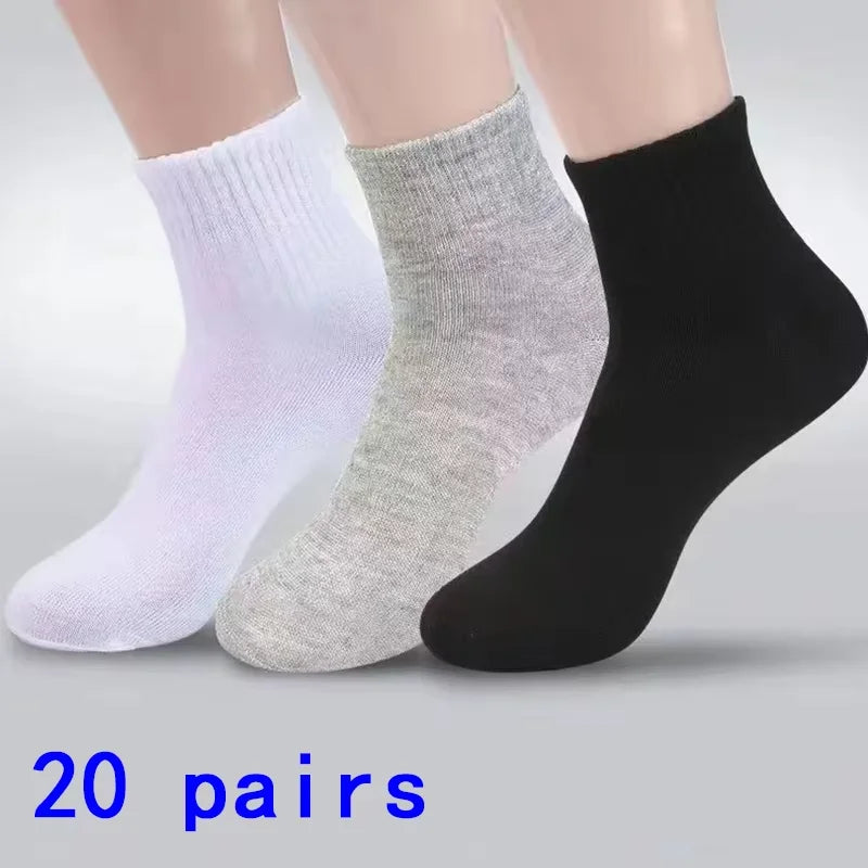 Ein Set aus drei Knöchelsocken in Weiß, Hellgrau und Schwarz wird auf einer Oberfläche präsentiert.