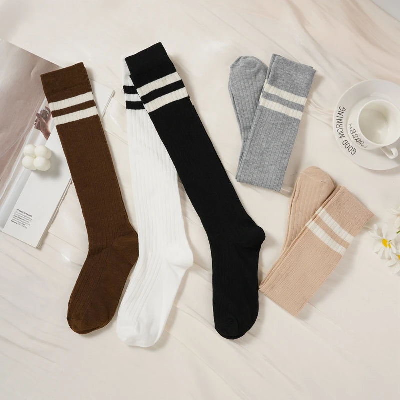 A collection of women's striped cotton knee high socks in brown, white, and black are displayed on a light surface.
