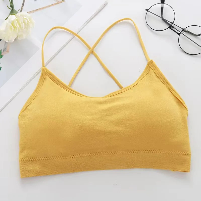 A yellow women's cross strap sports bra laid flat on a white surface.