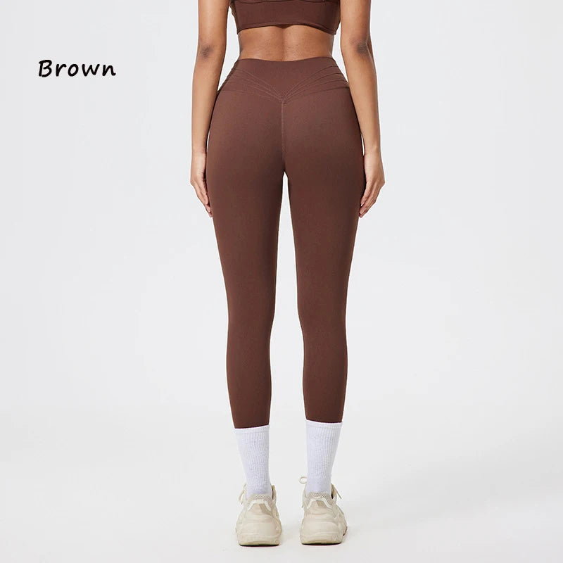 Braune, nahtlose Yoga-Leggings mit hoher Taille, getragen von einem Model, kombiniert mit weißen Socken und leichten Schuhen.