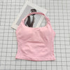 A pink seamless sports camisole top is laid on a grid, with a photo of a person in the background.