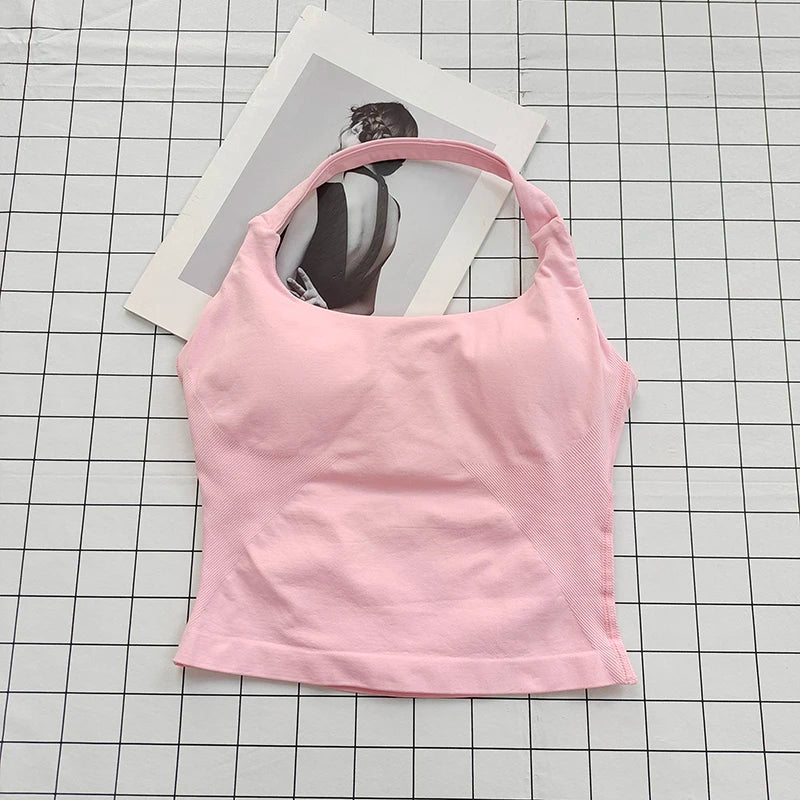 A pink seamless sports camisole top is laid on a grid, with a photo of a person in the background.