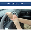 A hand wearing a beige breathable arm sleeve is gripping a car steering wheel.