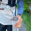 A hand is pouring water from a clear bottle into a translucent silicone water bottle for sports and hiking.