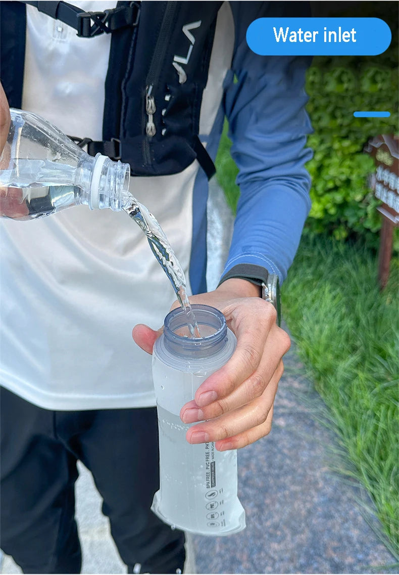 A hand is pouring water from a clear bottle into a translucent silicone water bottle for sports and hiking.