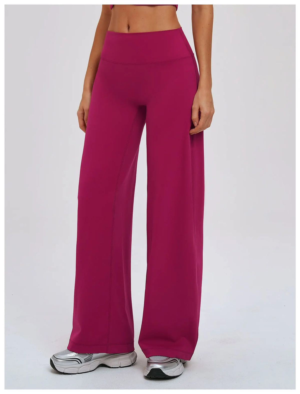 A model wearing magenta high-waist wide-leg yoga leggings and silver athletic shoes.