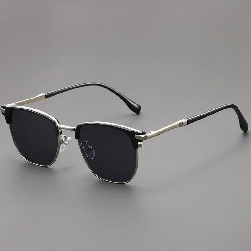 A pair of black sunglasses with a metal frame and UV400 protection resting on a gray surface.