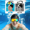 A man wearing orange anti-fog UV swim goggles is smiling underwater.