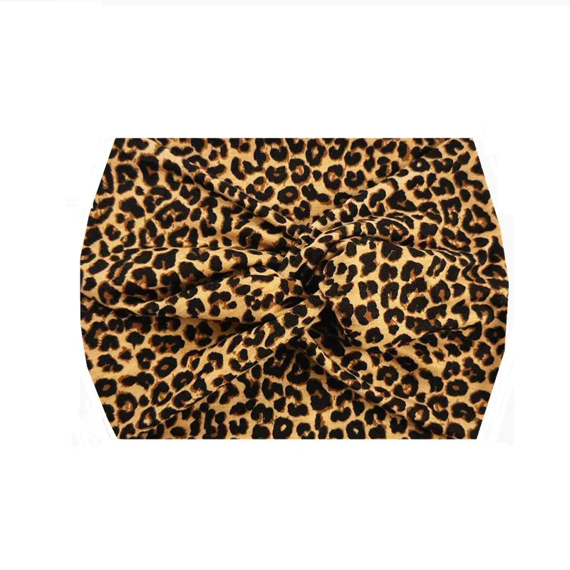 Bandeau de sport à imprimé léopard noir et tan, en tissu extensible, plié en nœud.