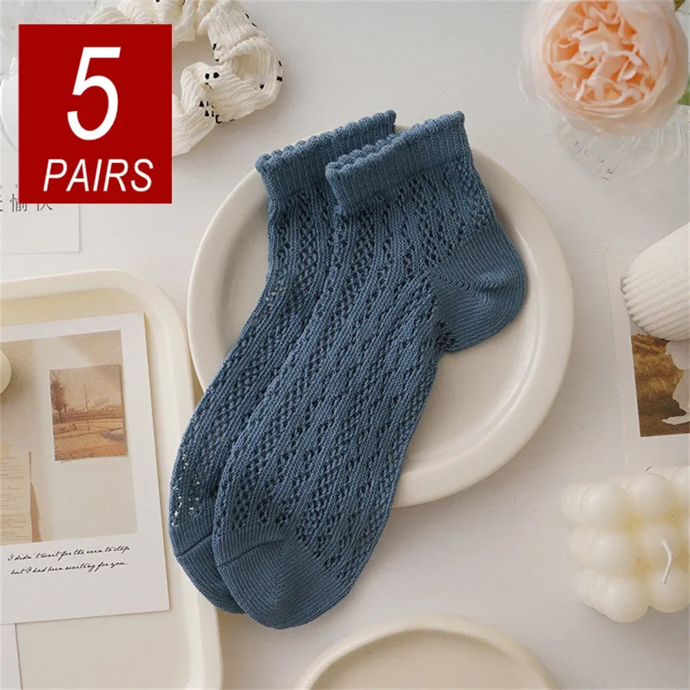 Five pairs of blue knitted mesh lace tube socks displayed on a white plate.