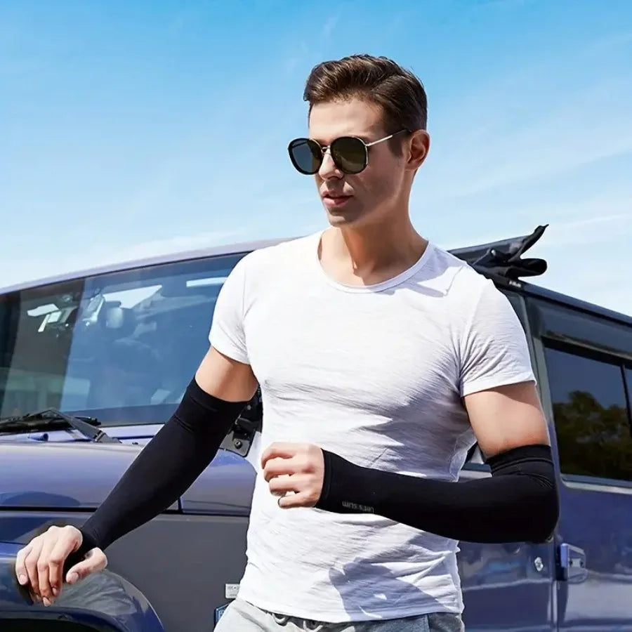 A man wearing white clothing and sunglasses stands next to a dark vehicle, displaying black sun protection arm sleeves.