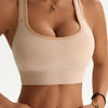 A model wearing a beige seamless racerback sports bra top and matching bottoms.
