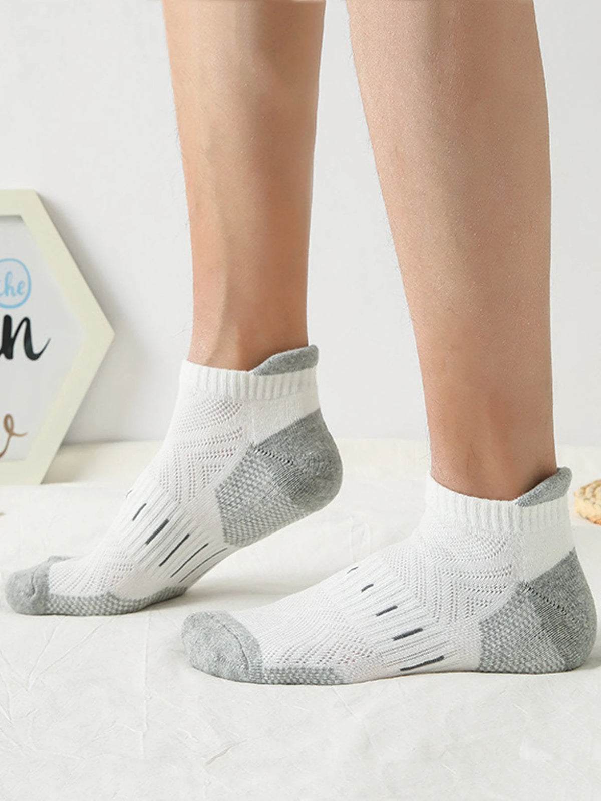 A pair of light gray and white athletic mesh ankle socks worn on a person's foot.