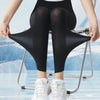 Leggings en peau de requin noire portés par une femme debout sur un rack métallique.