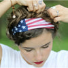 A person is adjusting a USA flag tube bandana and head wrap on their hair.