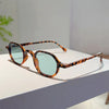 Vintage oval sunglasses with brown and black leopard print frames and light blue lenses resting on a white surface.
