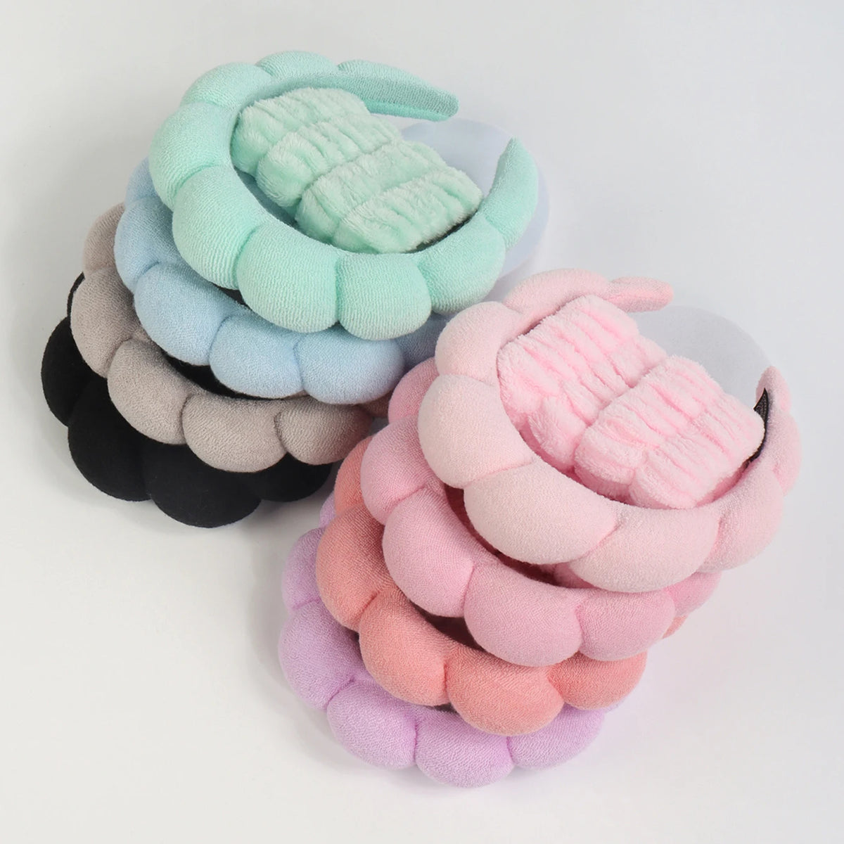 A set of pastel green, blue, and pink microfiber skincare headbands and wristbands.