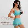 A woman models performance yoga shorts in teal fabric against a light gray background.