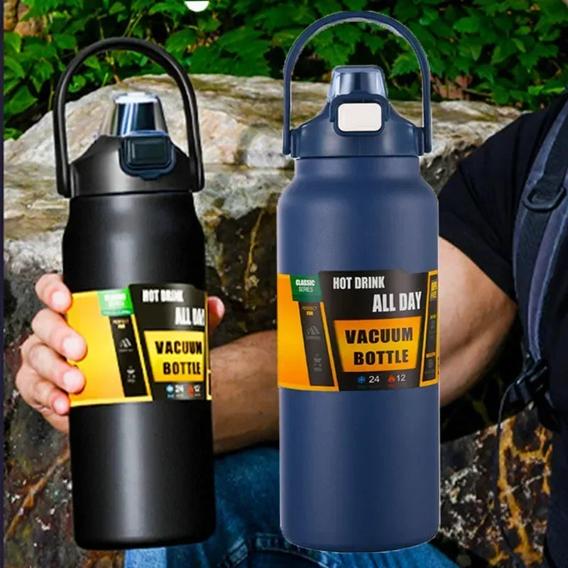 A dark blue insulated vacuum bottle with a black handle is held by a person outdoors.