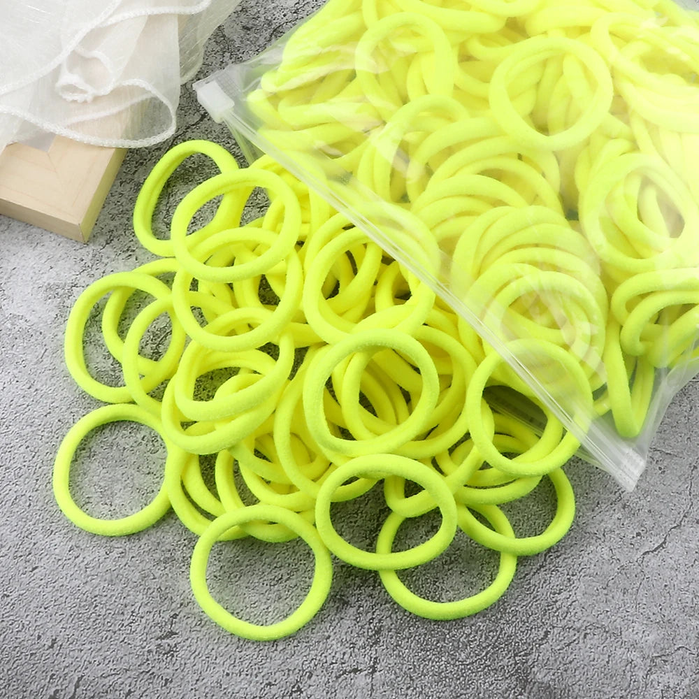 A pile of bright yellow elastic hair bands in various sizes and colors, packaged in clear plastic.