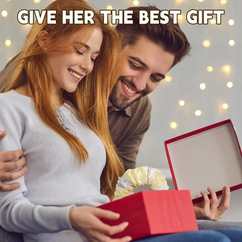 A smiling woman is holding a red gift box while a man looks at her, suggesting a gift for a heatless curling rod headband.