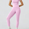 Eine Frau modelliert ein zweteiliges Yoga-Set mit pinkem Crop-Top und passenden Leggings.