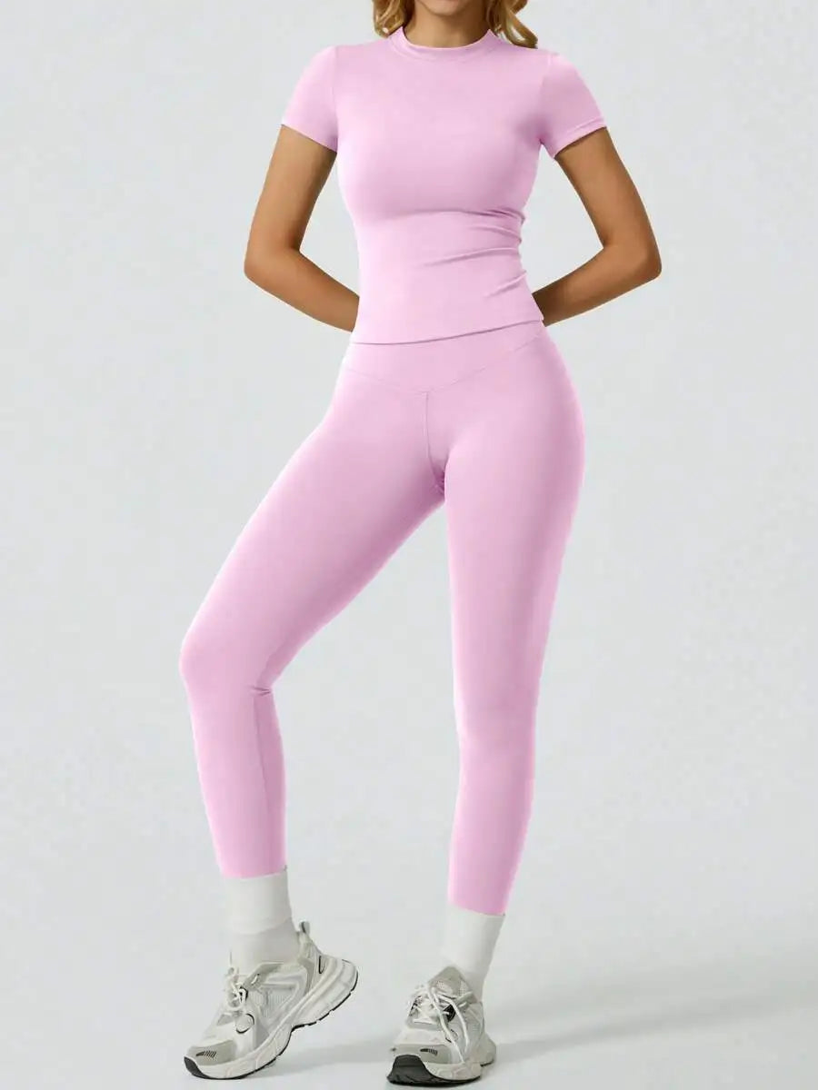 Eine Frau modelliert ein zweteiliges Yoga-Set mit pinkem Crop-Top und passenden Leggings.