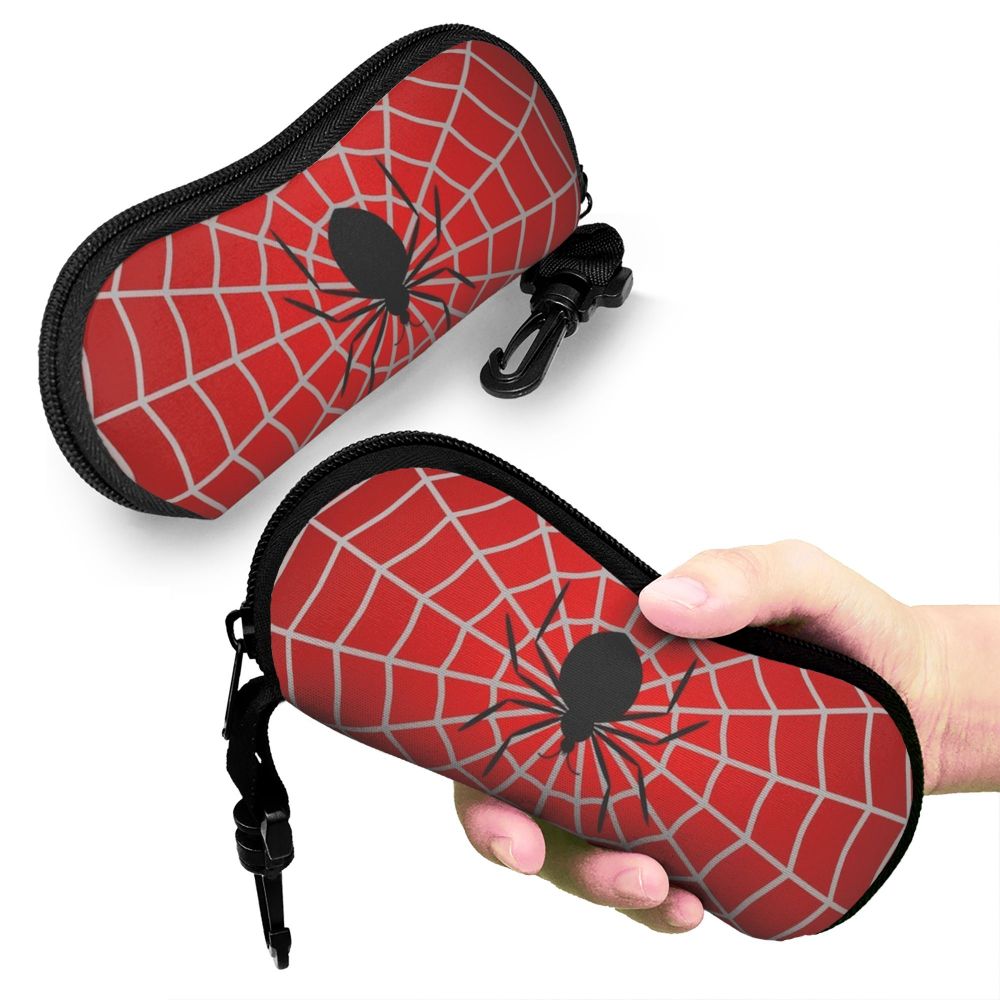 A red spider web patterned pouch for eyeglasses is being held by a hand.