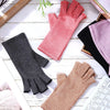 A collection of various colored compression hand gloves, including pink, black, and tan shades, displayed on a white wooden s