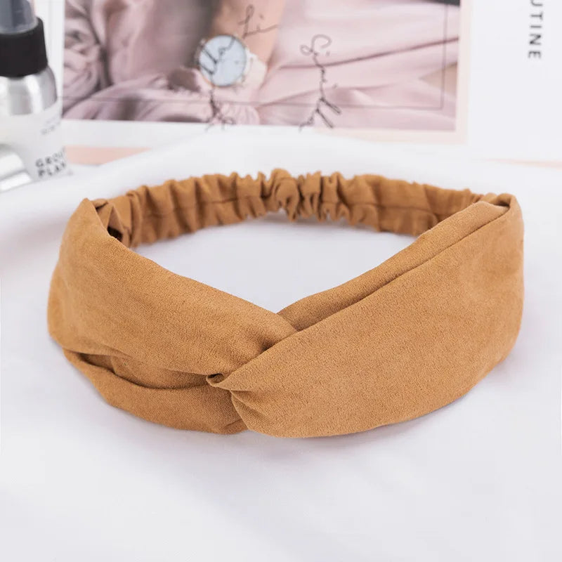 A brown fabric headband made of chiffon is shown lying on a white surface.