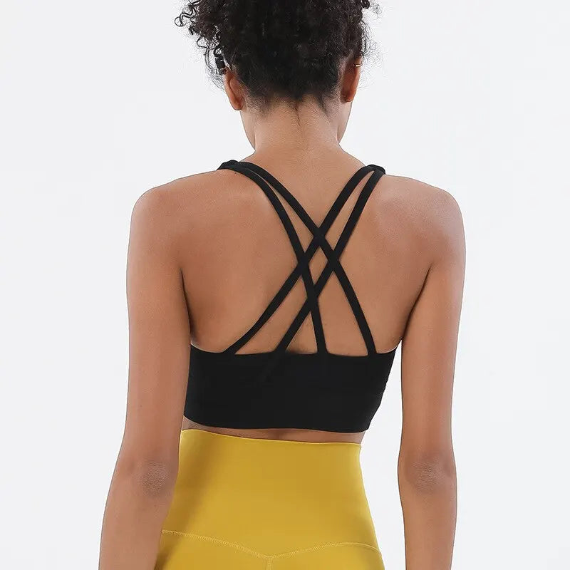 Rückansicht einer Frau in einem schwarzen, atmungsaktiven Nylon-Yoga-Sport-BH und gelben Sportunterhosen.