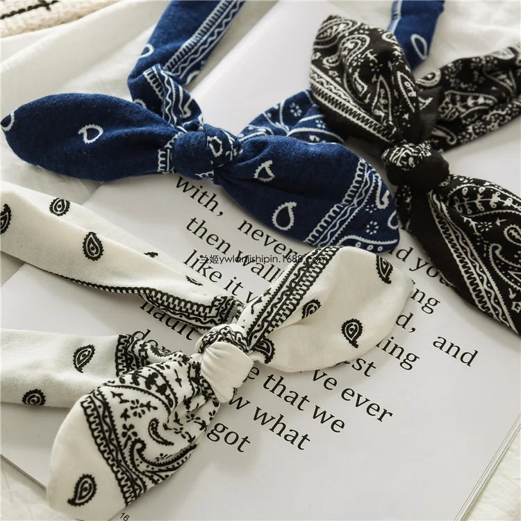 Gros plan de bandeaux de tête à motif paisley bohème bleu marine et blanc sur du papier.