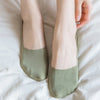 A pair of olive green silicone anti-slip summer socks resting on a white sheet.