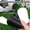 A hand holds a white and black mini shin guard made of EVA material on a green surface.