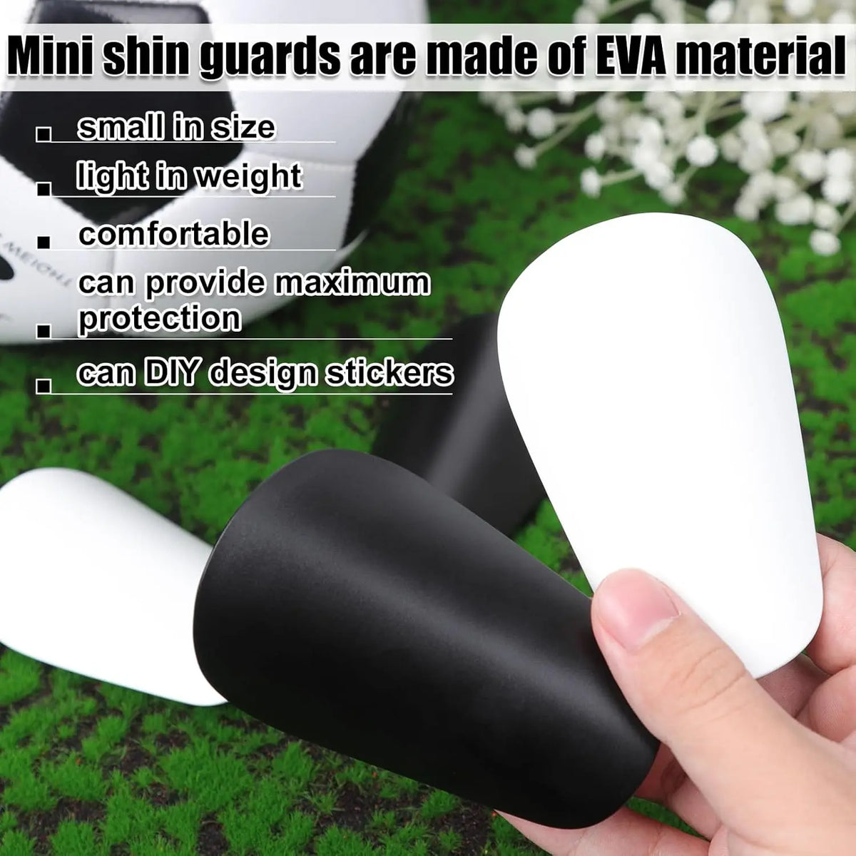 A hand holds a white and black mini shin guard made of EVA material on a green surface.