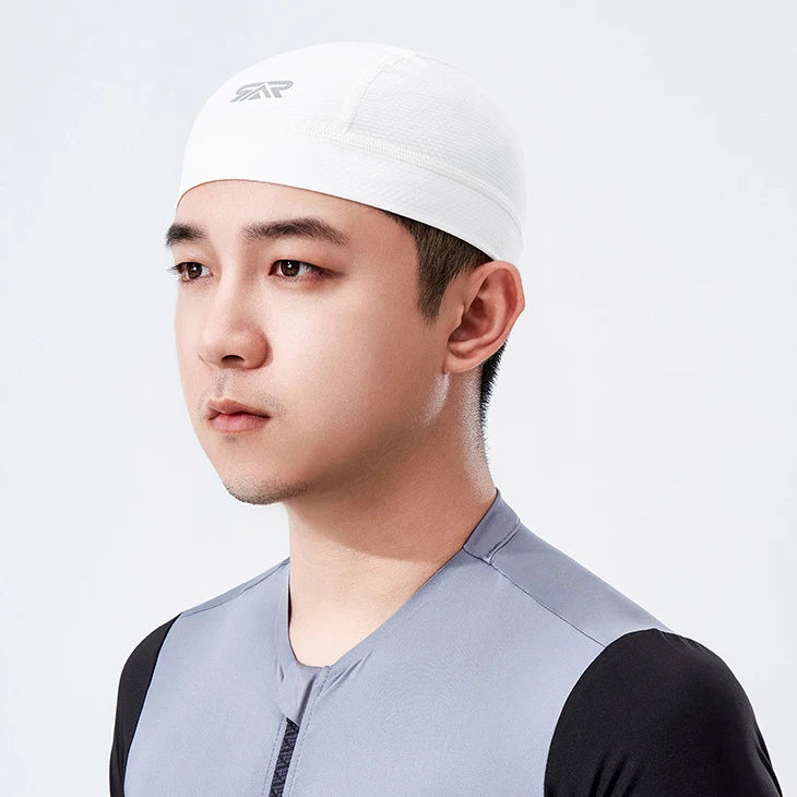 A close-up of a man wearing a white cycling cap with black accents against a light background.