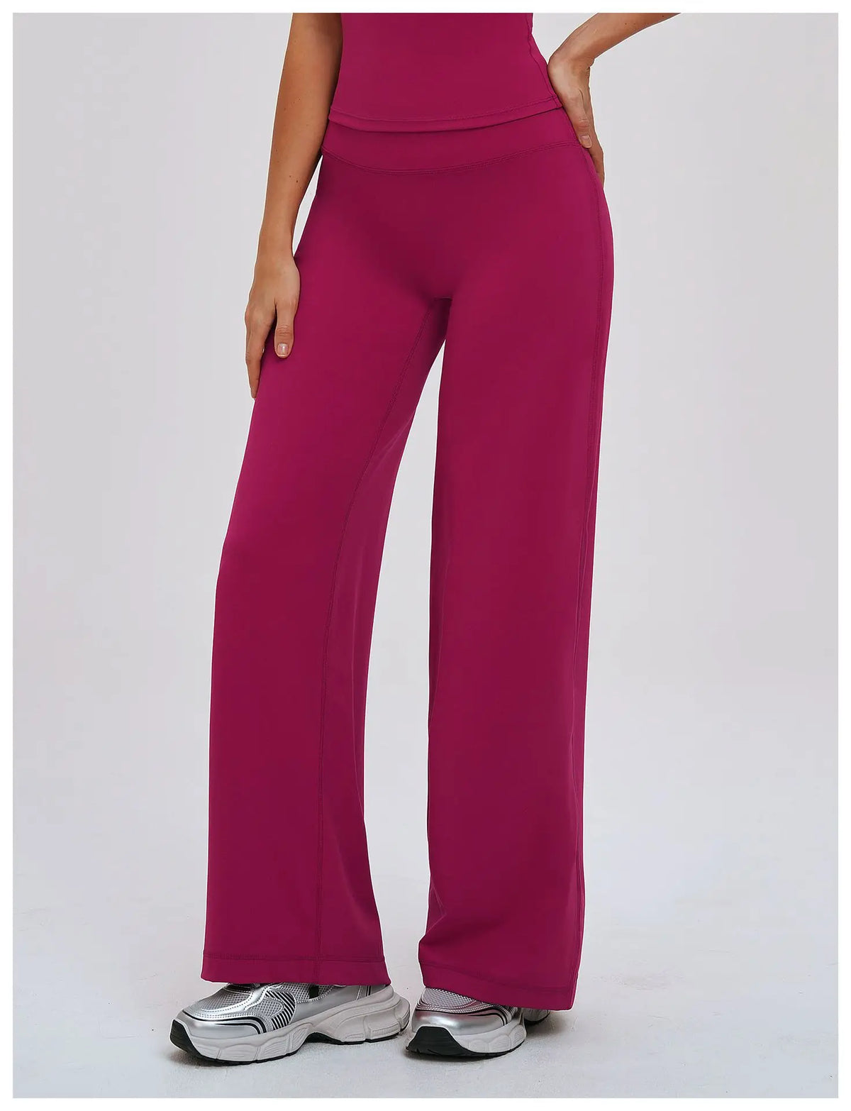 A woman wearing magenta high-waist wide-leg yoga leggings and silver sneakers.